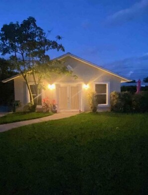 Una casa con un césped cuidado y una puerta principal iluminada por luces exteriores.
