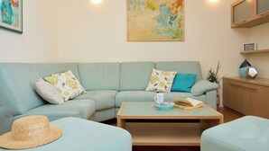 A living room with a light blue sofa, a coffee table, and a painting on the wall. - Apartment Terra - Three Bedroom Apartment, Sleeps 5 (Dubrovnik)