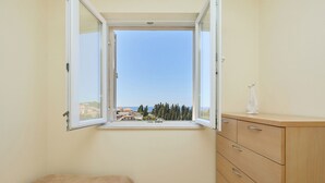 A bedroom with a window, a bed, and a wooden dresser. - Apartment Terra - Three Bedroom Apartment, Sleeps 5 (Dubrovnik)