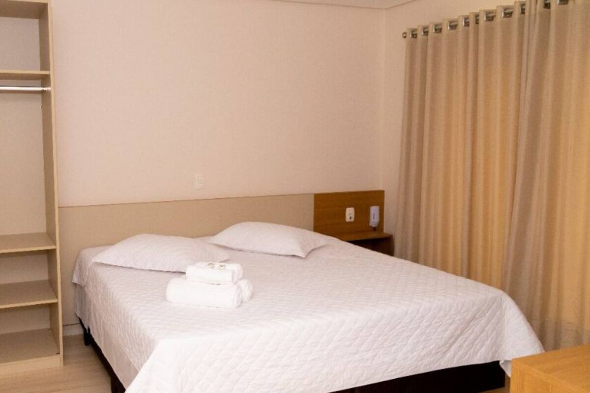 A hotel room with a bed, a wardrobe, and a nightstand.