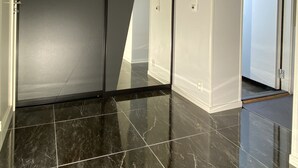 A hallway with a sliding door, tiled floor, and a door leading to another room. - Newly renovated basement apartment with nice view (Møre og Romsdal)