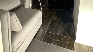A corner of a room with a grey sofa, a black curtain, and a white floor lamp. - Newly renovated basement apartment with nice view (Møre og Romsdal)