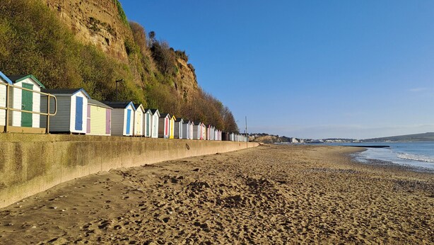 Une plage bordée d’une rangée de cabanes de plage aux couleurs vives.