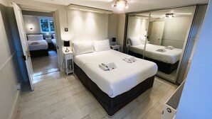Una habitación de hotel con una cama grande, mesitas de noche, un espejo y una ventana.