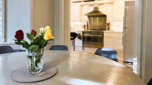 Una mesa de comedor con un jarrón de flores en el centro.