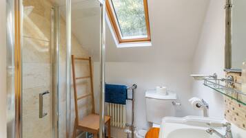 A bathroom with a glass shower enclosure, a wooden ladder, a towel rack, a toilet, and a sink with a mirror.