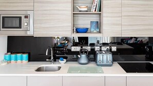 A modern kitchen with a microwave, toaster, kettle, and a sink. - New Horizon (Sandown)