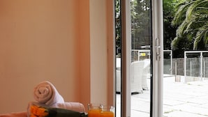 A breakfast tray with croissants, strawberries, and orange juice on a table by a window with a view of a palm tree and a building. - No 1 Ashey (Ryde)