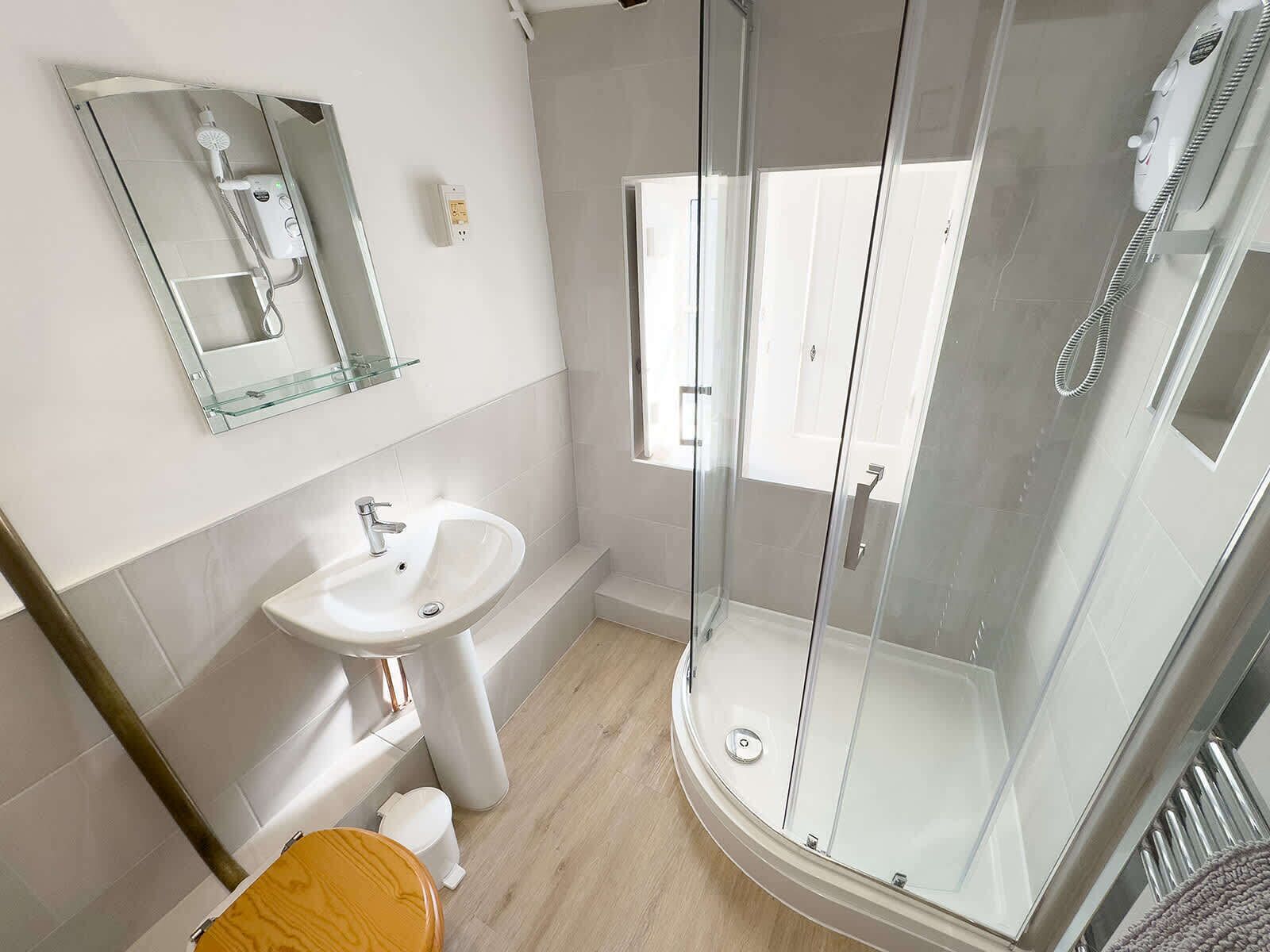 A modern bathroom with a glass-enclosed shower, a white sink, and a toilet.