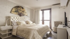 Ein Schlafzimmer mit einem großen Bett, einem Nachttisch, einem Stuhl, einem Schreibtisch und einem Wandventilator.