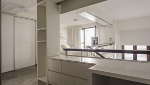 Ein modernes Hotelzimmer mit großem Fenster, Balkon und Blick auf die Stadtlandschaft.