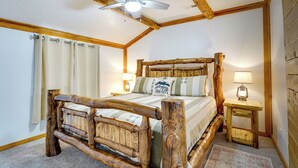 A bedroom with a wooden bed frame, a ceiling fan, and a nightstand with a lamp. - The Zen Den (Cedar City)