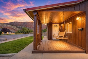 A wooden cabin with a porch, a swing, and a door with a number. - The Zen Den (Cedar City)
