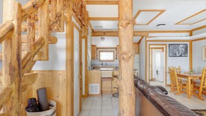 A wooden interior with a staircase, a kitchen area, and a dining table. - The Zen Den (Cedar City)