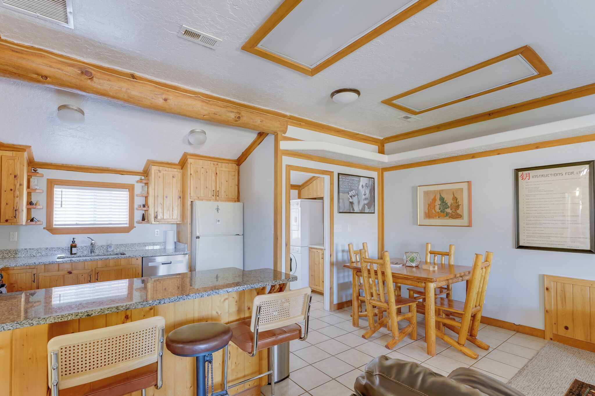 A kitchen with wooden cabinets, a granite countertop, and a dining area with a wooden table and chairs.