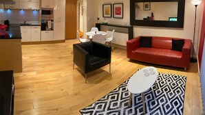 A modern living room with a black leather sofa, a red leather couch, a white coffee table, and a patterned rug.