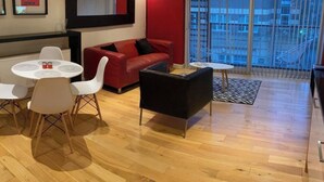 A modern living room with a red sofa, white chairs, a black coffee table, and a small round table with salt and pepper shakers.