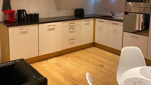 A modern kitchen with white cabinets, a black countertop, and a wooden floor.