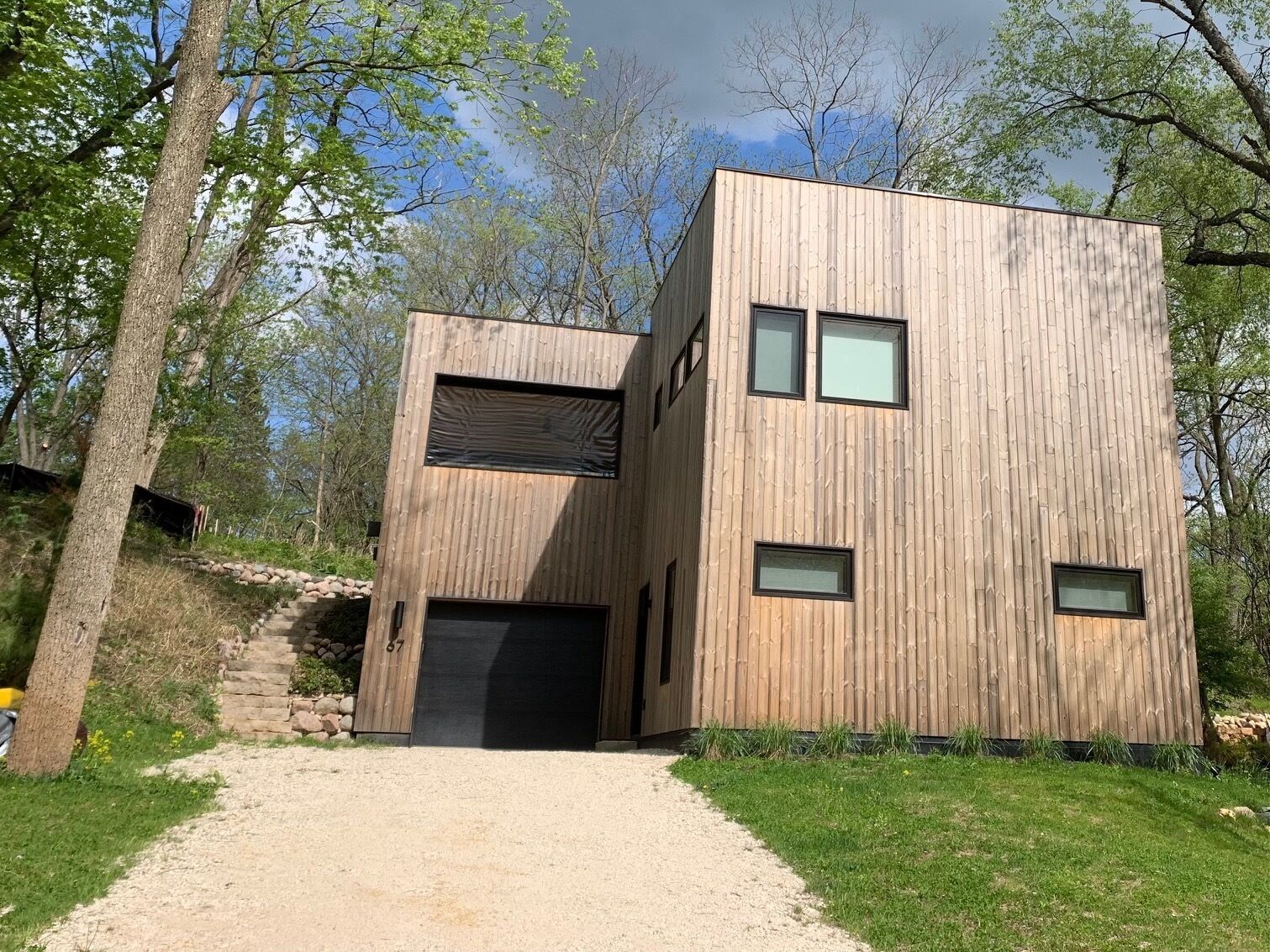 Un bâtiment moderne en bois, doté d’une entrée centrale, de nombreuses fenêtres et d’un chemin de gravier menant à l’entrée.