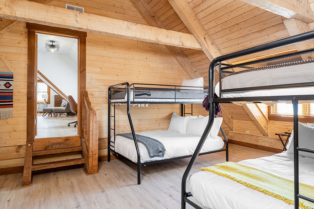 Eine Holzhütte mit drei Etagenbetten, einer Treppe und Blick ins Freie.