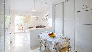 Uma cozinha moderna com área de refeições, armários brancos e uma fruteira sobre a mesa.