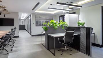 Un espace de bureau moderne doté d’une grande table de conférence, de postes de travail individuels et offrant une vue sur la rue grâce à une porte vitrée.