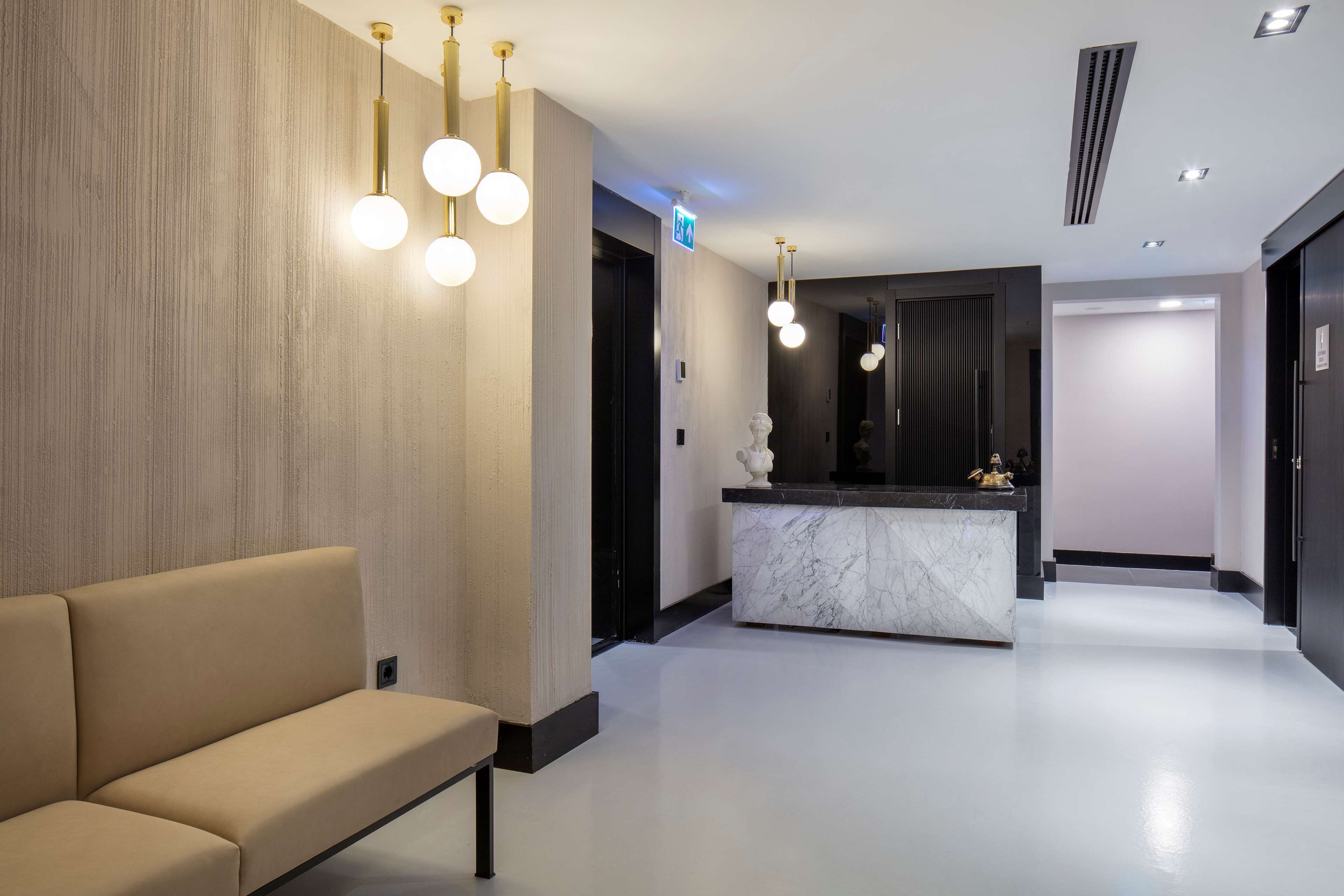 A modern lobby with a reception desk, a sofa, and pendant lighting.