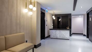 A modern lobby with a reception desk, a sofa, and pendant lighting.