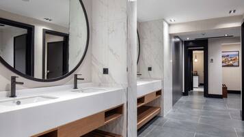 A modern bathroom with two sinks, wooden shelves, and a large mirror.