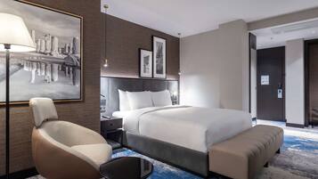 Una habitación de hotel moderna con una cama grande, una silla, un escritorio y una lámpara de pared.
