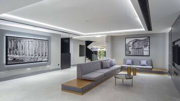 A modern lobby with a grey sofa, a coffee table, and a large framed picture on the wall.