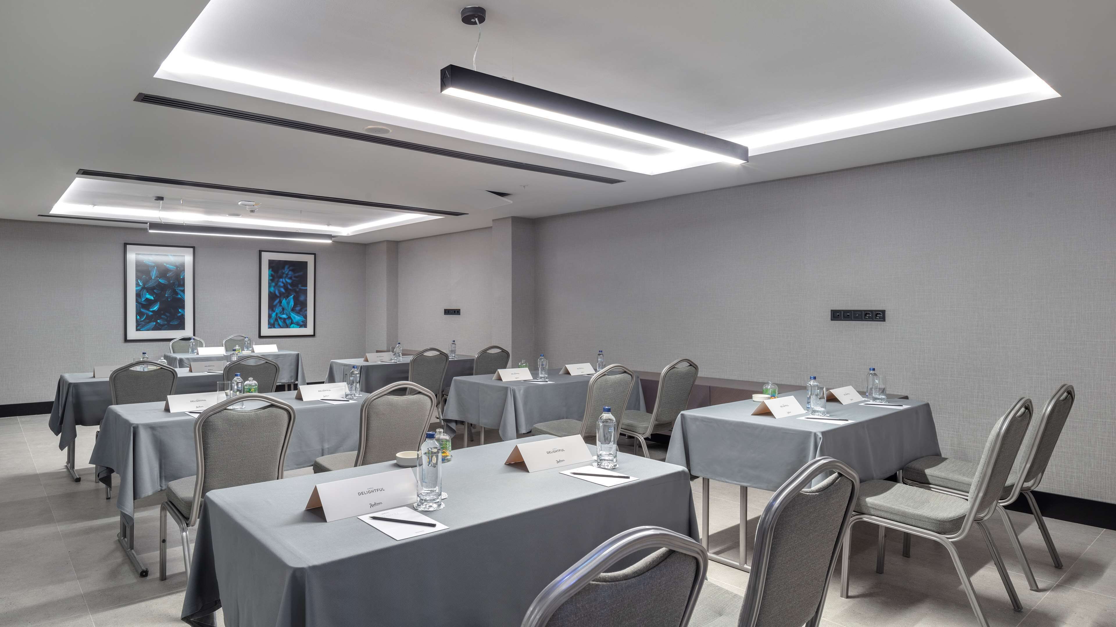 A conference room with tables, chairs, nameplates, water bottles, and framed artwork on the walls.
