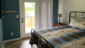 A bedroom with a bed, a nightstand, a lamp, a ceiling fan, and a door leading to a balcony. - Conveniently located New Cabin at Lake Mille Lacs  (Isle)