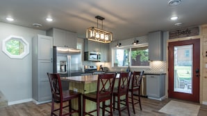 A modern kitchen with a central island, built-in appliances, and a farmhouse-style door. - Conveniently located New Cabin at Lake Mille Lacs  (Isle)