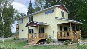 A two-story house with a covered porch and a small deck. - Conveniently located New Cabin at Lake Mille Lacs  (Isle)