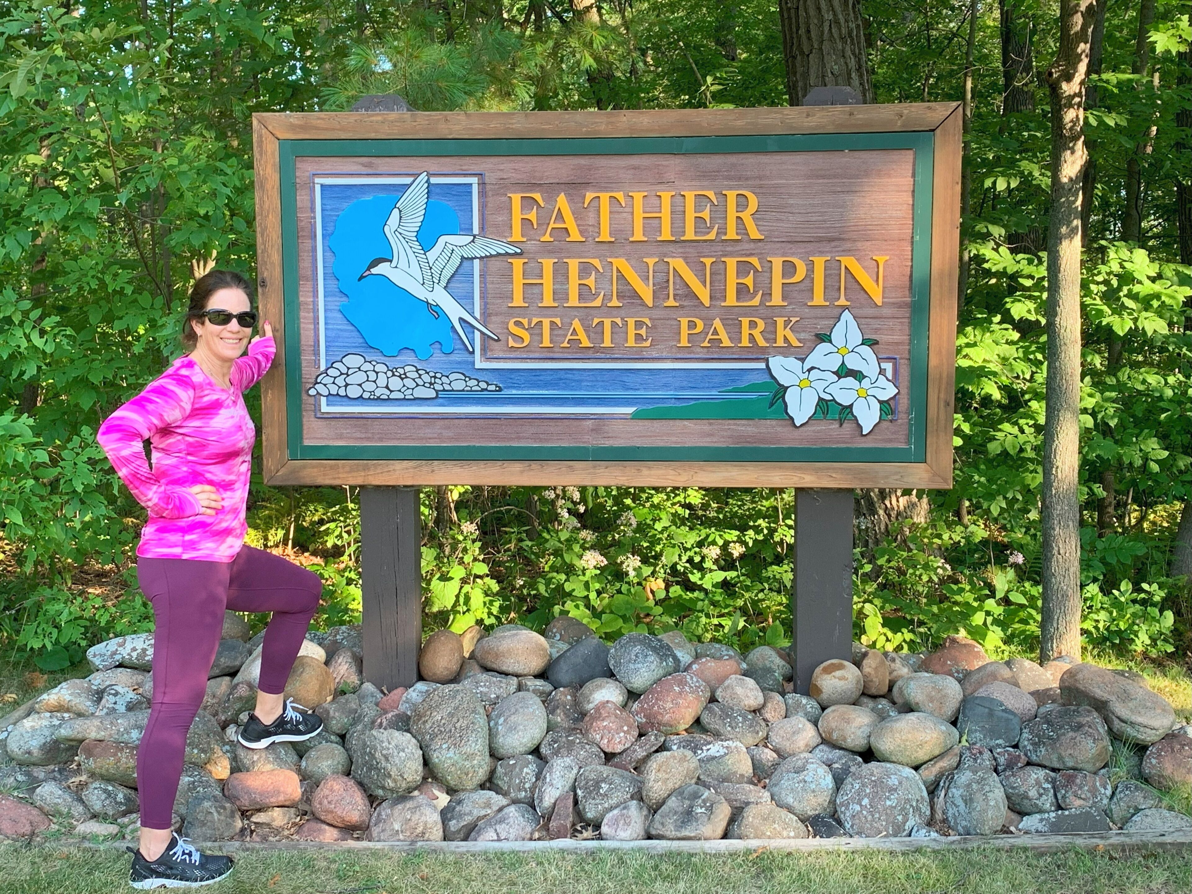 A sign for Father Hennepin State Park with a bird and flowers illustration.