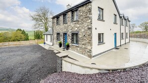 Une maison à deux étages avec une façade en pierre, une porte bleue et une allée pavée.