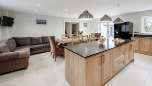 Une cuisine moderne dotée d’un îlot central, de meubles en bois et de luminaires suspendus.