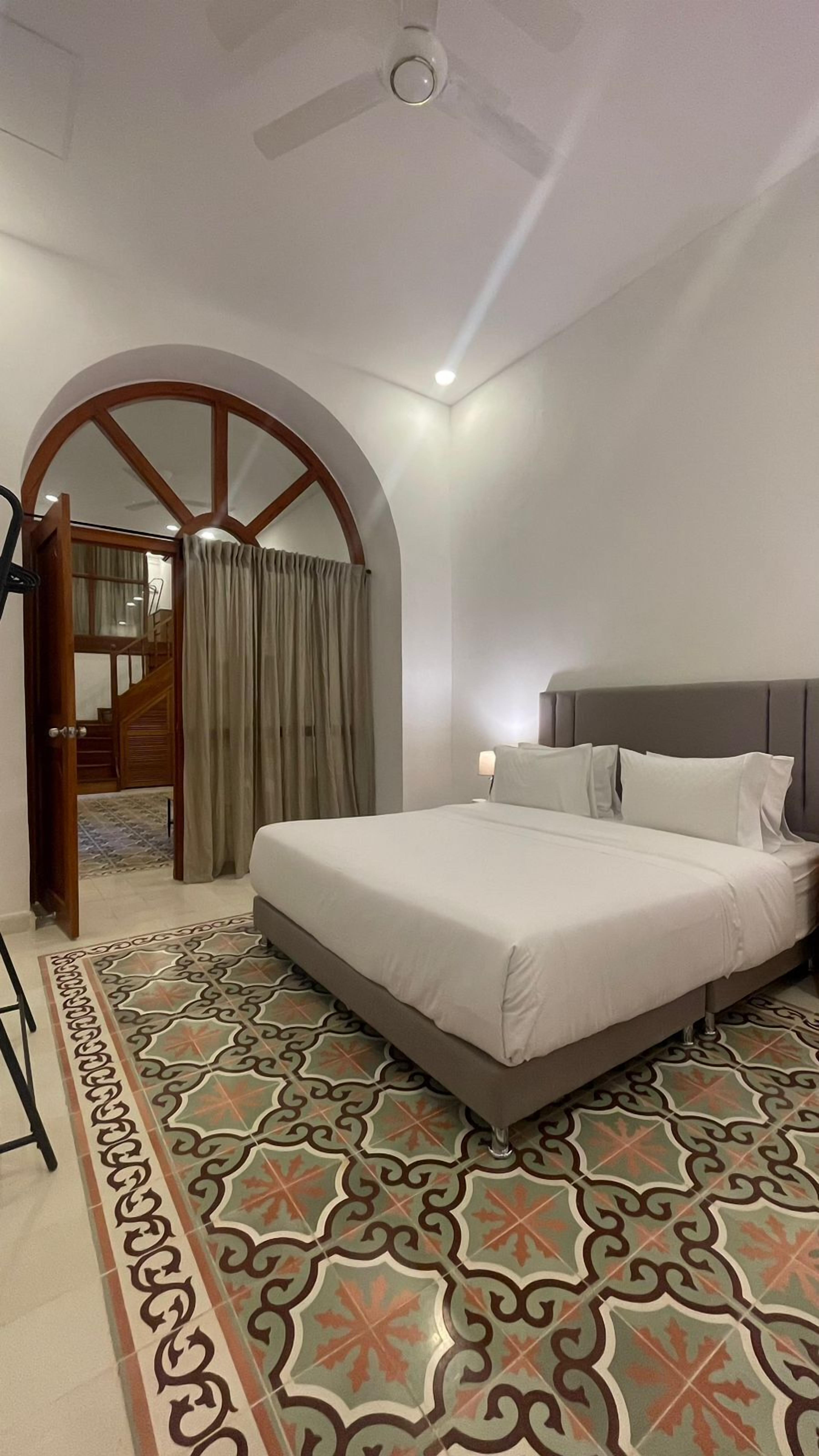 Ein Hotelzimmer mit einem Bett, einem gemusterten Teppich, einer Holztür und einer Treppe.