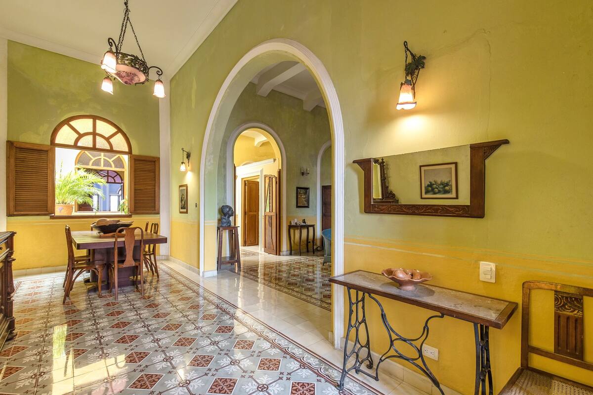 A dining area with a table and chairs, a patterned floor, and a hallway with arches.