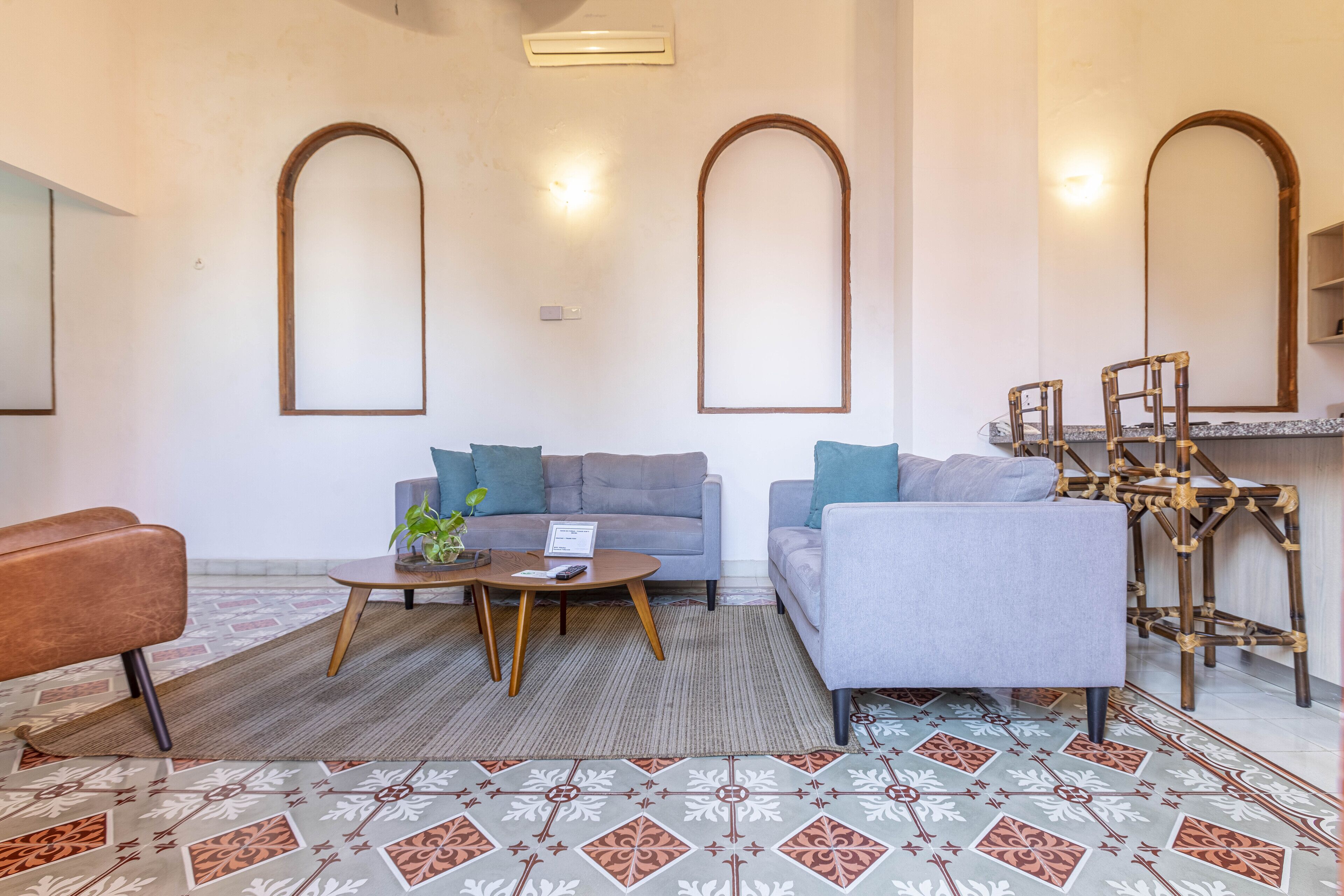 A modern living room with a grey sofa, a brown leather chair, and a patterned rug.