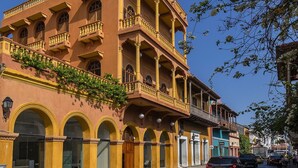 A multi-story building with balconies, arched windows, and a street view.
