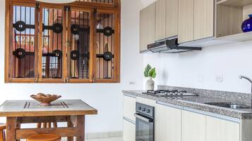 A kitchen with a wooden table, stools, a stove, and a sink.