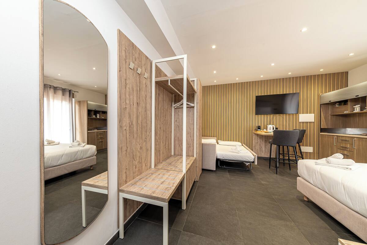 Une chambre d’hôtel moderne équipée d’un lit, d’un bureau, d’une chaise, d’un miroir et d’une télévision.