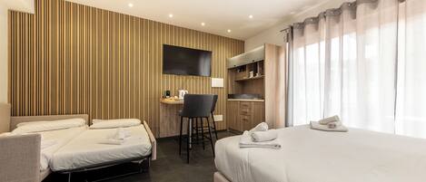 Une chambre d’hôtel équipée d’un lit, d’un bureau, d’une chaise, d’une télévision et d’une kitchenette.