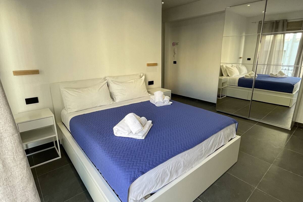 Une chambre d’hôtel moderne avec un grand lit, une table de chevet, un miroir et une petite table.