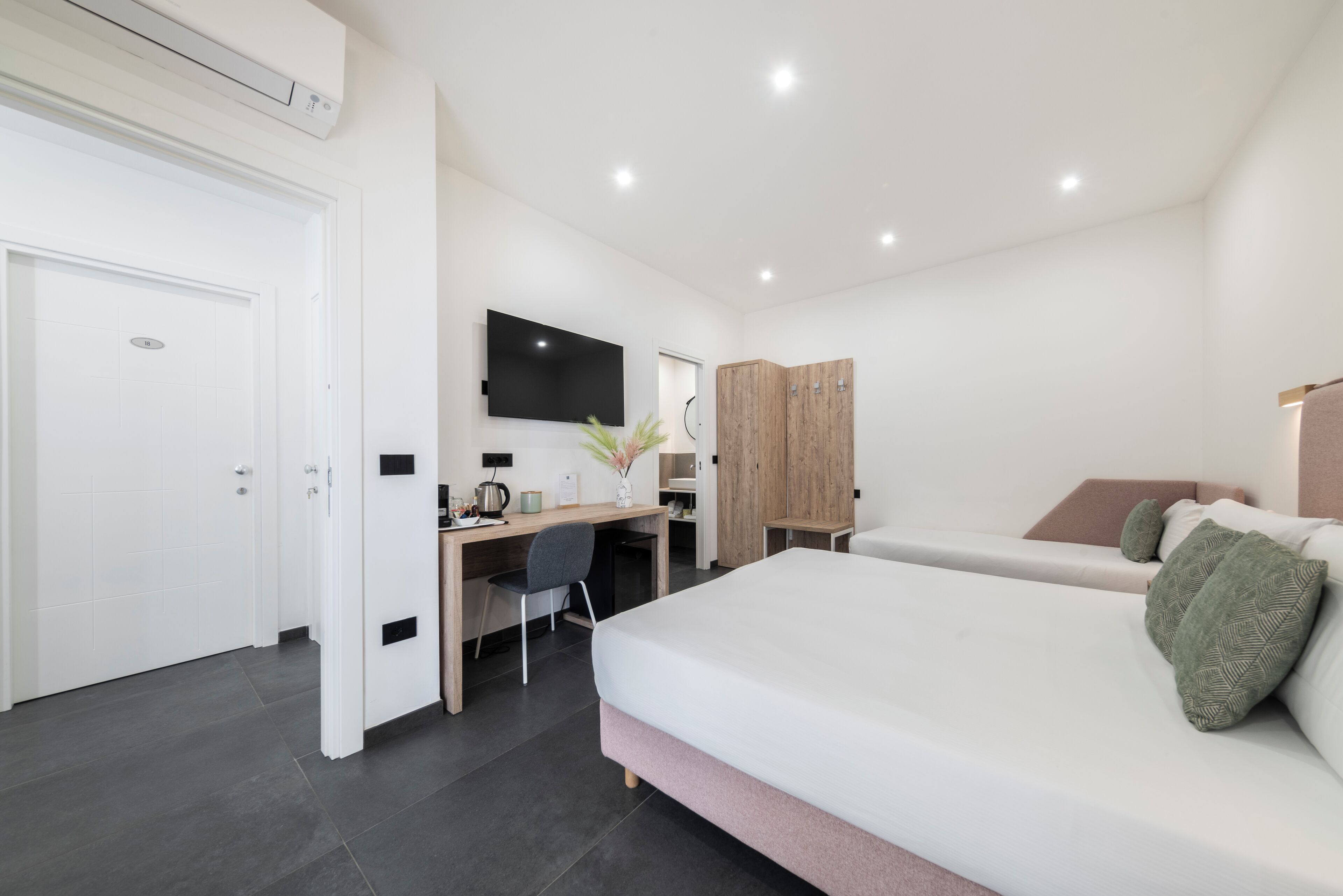 A modern bedroom with a bed, desk, and wardrobe.
