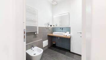 A modern bathroom with a bidet, a sink, and a mirror.