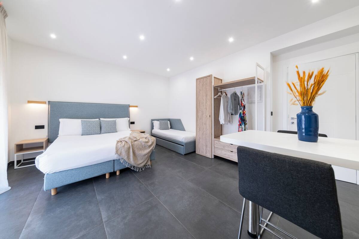 Une chambre moderne avec un lit, un petit canapé, un bureau et une armoire.