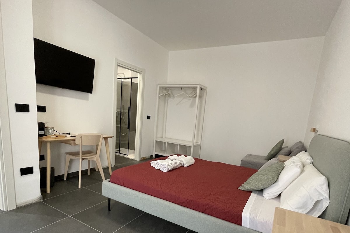 Une chambre à coucher comprenant un lit, un bureau, une chaise, une télévision et une armoire.